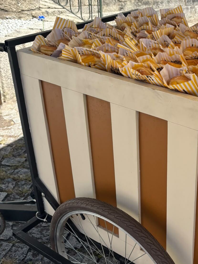 O carrinho da bicicleta cheio de bolinhas embrulhadas em papel às riscas, na calçada de granito.